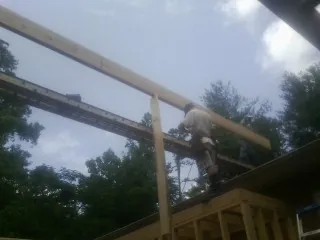 Carpenter setting a ridge beam over a new addition frame — Ice Dam Removal by Roofing Brothers in Acushnet