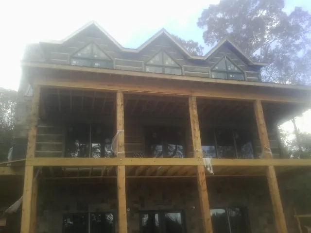 Dormers and porch framing on a large log home under construction — Roof Coating work by our crew in Acushnet