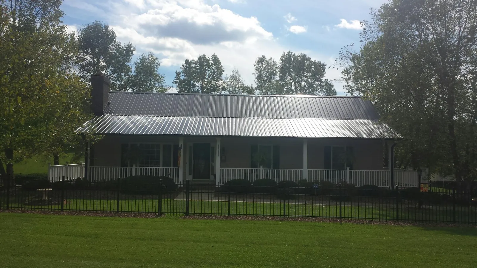 Gray metal roof on a brick ranch with a full width front porch — Gutter Guard Installation work by our crew in Acushnet