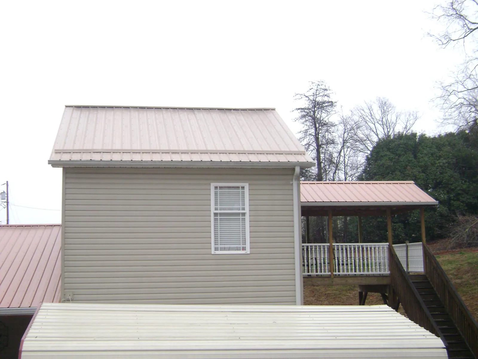 Tan metal roofs on a two story addition and attached porch, from a Roof Replacement job in Acushnet