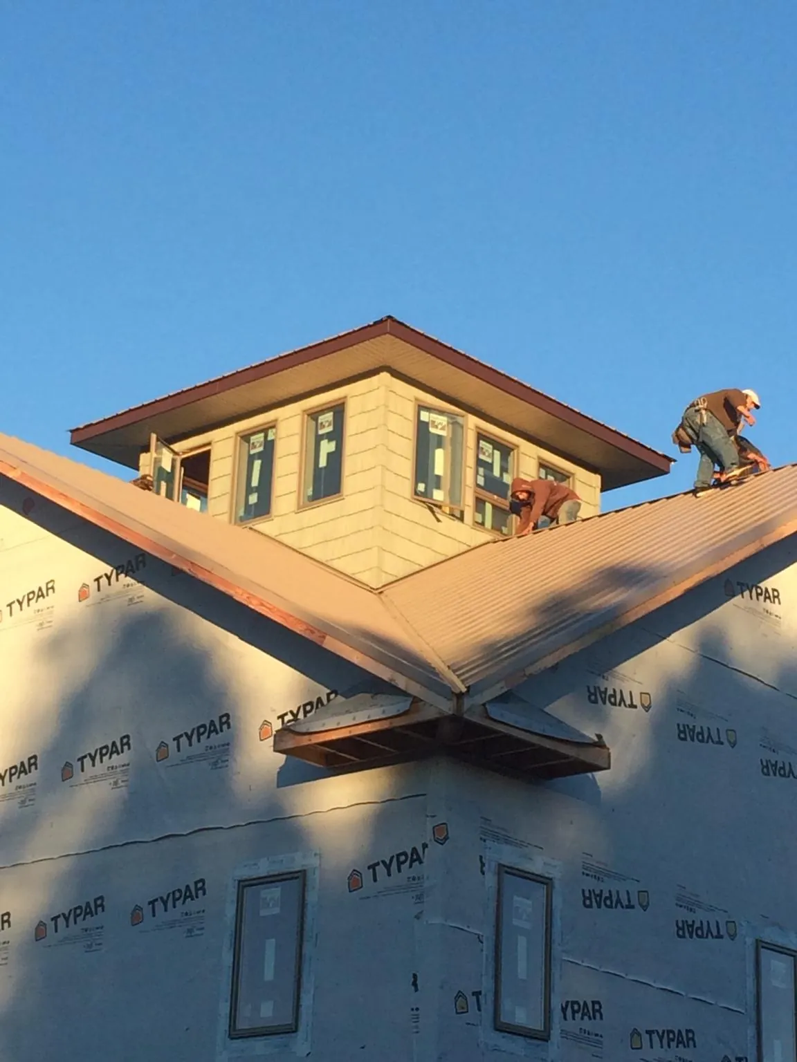Roofers working around a rooftop cupola on a new metal roof at sunset — Roof Waterproofing in Acushnet by Roofing Brothers